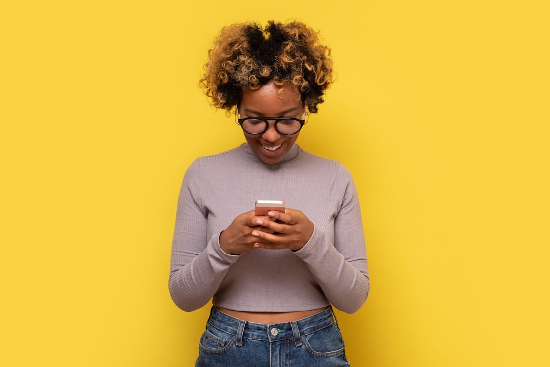 African young woman types text message on cell phone, enjoys online communication